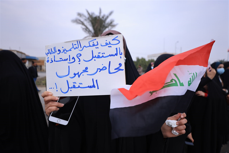 إحدى المحاضرات المجانيات منذ سنين ترفع لافتة في الاحتجاجات الأخيرة في مدينة بغداد